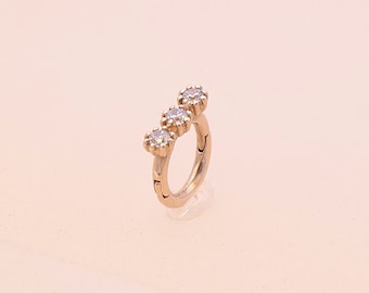 May include: A gold hoop earring with three small, clear cubic zirconia stones set in a row.