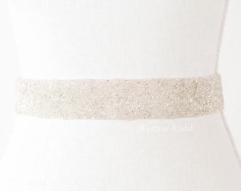Op de afbeelding: Een witte parelband voor een bruidsjurk. De band is gemaakt van kleine, witte parels die aan elkaar zijn genaaid om een ​​delicate en elegante look te creëren. De band is ongeveer 3,8 cm breed en perfect om een ​​toets van glans toe te voegen aan elke bruidsjurk.