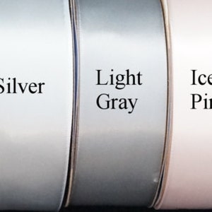 Op de afbeelding: Een selectie van lintrollen in verschillende kleuren, waaronder wit, ivoor, licht ivoor, champagne, zilver, lichtgrijs, ijsroze, lichtblauw, tiffanyblauw, donkerblauw en zwart.