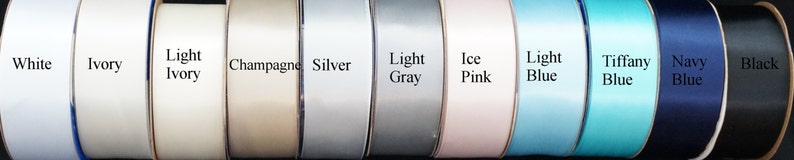 Op de afbeelding: Een selectie van lintrollen in verschillende kleuren, waaronder wit, ivoor, licht ivoor, champagne, zilver, lichtgrijs, ijsroze, lichtblauw, tiffanyblauw, donkerblauw en zwart.