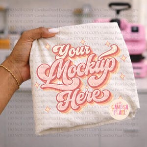 Peut inclure: Un t-shirt blanc plié avec le texte "Your Mockup Here" dans un design rétro rose et orange. Le t-shirt est tenu par une main avec un bracelet doré. Le design comprend des étoiles et le logo Candisa Pearl.