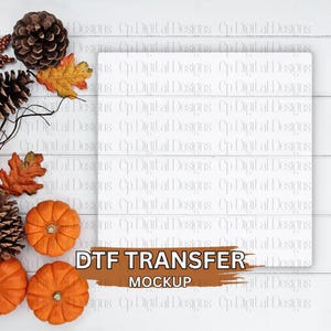 Może przedstawiać: Jesienny mockup z białą prostokątną powierzchnią i tekstem "DTF TRANSFER MOCKUP". Obraz zawiera pomarańczowe dynie, szyszki i jesienne liście, ułożone na białym drewnianym tle.