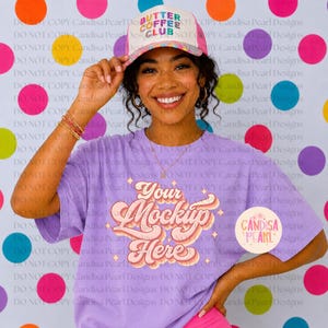 May include: A lavender t-shirt featuring the text Your Mockup Here in a retro-style font with star accents. The shirt is paired with a white trucker hat that displays the text BUTTER COFFEE CLUB in colorful letters on the front panel.