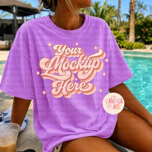 May include: A lilac t-shirt with the text "Your Mockup Here" in a retro font. The design features a layered, multi-coloured effect with pink, orange, and white hues. The shirt is a short-sleeved, oversized style.