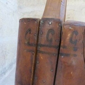 May include: Close-up of a wooden boot form with the letters "C.G.C" stamped on the side.