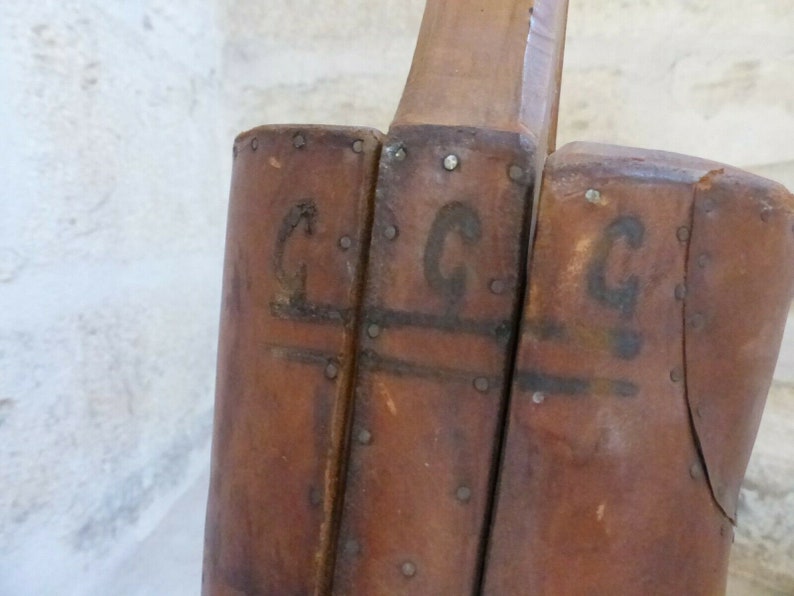 May include: Close-up of a wooden boot form with the letters "C.G.C" stamped on the side.
