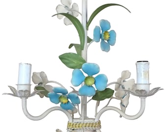 May include: White metal chandelier with blue and white flowers. The chandelier has three lights and a white cord.