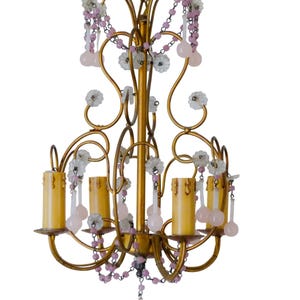 Peut inclure: Un lustre doré vintage avec un design floral. Le lustre comporte six lumières en forme de bougie, ornées d'accents perlés roses et blancs. Le luminaire a une esthétique classique et élégante, parfaite pour ajouter une touche de charme vintage.