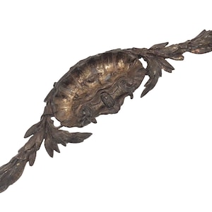 以下が含まれることがあります： 中央に貝殻のようなデザイン、両側に葉と蔓の要素がある、アンティークで装飾的な金属製の装飾品。くすんだ金とブロンズの仕上げで、古さと複雑な職人技を連想させます。 全体的な形状は細長く、対称的です。