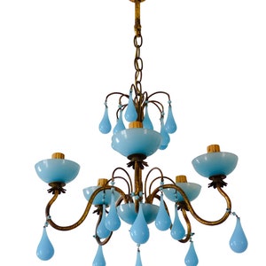 May include: A gold chandelier with blue glass teardrop-shaped pendants and five light bulbs. The chandelier has a chain hanging from the ceiling.