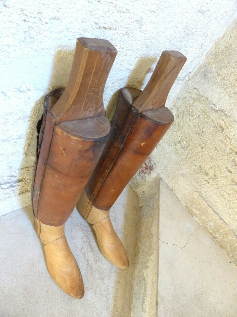 May include: Two wooden boot forms, one brown and one light brown, with a light brown wooden base. The forms are made of wood and have a smooth finish.