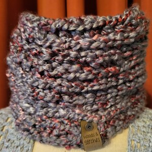 May include: A gray and red knitted neck warmer with a brown leather tag that says "Woods & Stitches".