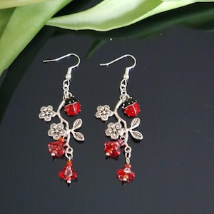 May include: Silver dangle earrings with red and black ladybug charms and red glass flower beads.