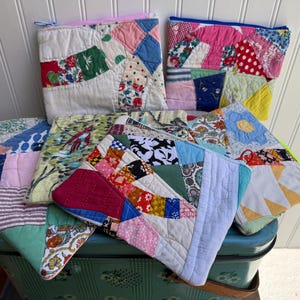 May include: A collection of handmade patchwork pouches and quilted pot holders in various sizes and shapes. The items feature a variety of colorful fabric scraps with floral, geometric, and abstract patterns. The pouches have zippers.