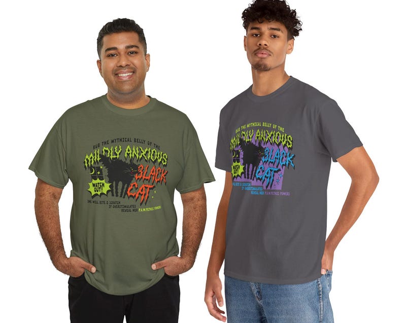K&ouml;nnte beinhalten: Zwei Personen tragen T-Shirts mit einem grafischen Design. Das Design zeigt den Text "AND THE MYTHICAL BELLY OF THE MILDLY ANXIOUS BLACK CAT" mit einer schwarzen Katzenillustration. Die Shirts sind olivgr&uuml;n und anthrazitgrau.