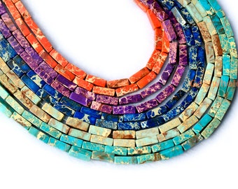 Può includere: Primo piano di una collana di perline di pietre preziose multicolori. Le perline sono rettangolari e hanno un motivo a martellina. I colori delle perline sono turchese, blu, viola, arancio e rosso.