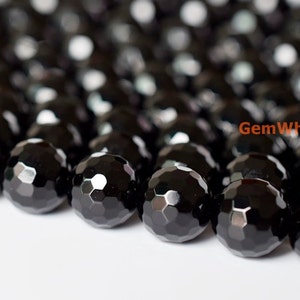 May include: Close-up of a collection of faceted black beads. The beads have a glossy, reflective surface and a geometric pattern. The beads are likely used for jewelry making or crafting.