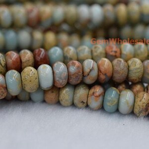 May include: A strand of light blue, brown, and beige jasper beads. The beads are round and have a smooth, polished finish. GemWholesale is printed on the image.