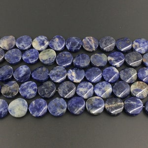 May include: A strand of blue and white oval-shaped gemstone beads. The beads are made of natural sodalite and have a smooth, polished finish.
