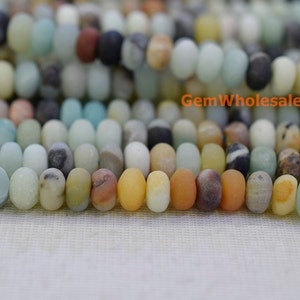 May include: Close-up of a strand of oval-shaped gemstone beads in various colors, including blue, yellow, brown, and white. The beads are strung together, creating a textured and colorful pattern. The beads are approximately 0.8 cm in length.