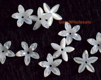 Könnte beinhalten: Zehn weiße Perlmutt-Blumen-Verzierungen mit einem Loch in der Mitte. Die Blumen haben einen Durchmesser von etwa 2,5 cm.
