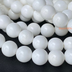 May include: A strand of white round beads made of polished white shell. The beads are smooth and glossy.