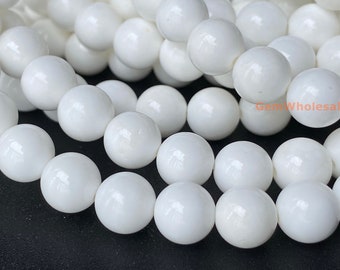 May include: A strand of white round beads made of polished white shell. The beads are smooth and glossy.