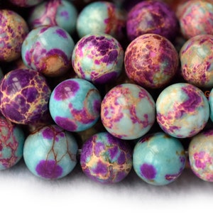 May include: Close-up of a strand of round, blue, purple, and white marbled gemstone beads. The beads are smooth and polished.