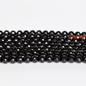 May include: Strands of faceted black beads, likely onyx or a similar gemstone, are displayed against a white background. The beads are round and have a polished, reflective surface. The image showcases the beads' color and texture.
