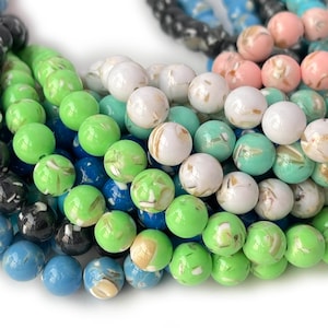 May include: A strand of round, colourful beads with a marbled effect. The beads are in shades of green, blue, white, and black.