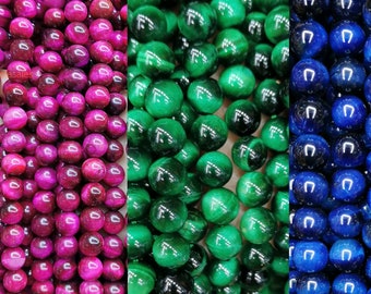May include: Three strands of round, smooth beads. The beads are made of tiger's eye stone and are in shades of pink, green, and blue.