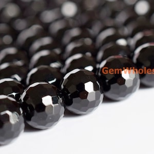 May include: Close-up of a strand of faceted black beads. The beads are round with multiple flat surfaces, creating a sparkling effect. The beads are arranged closely together, suggesting they are strung for jewelry making. The text "GemWholesale" is visible.