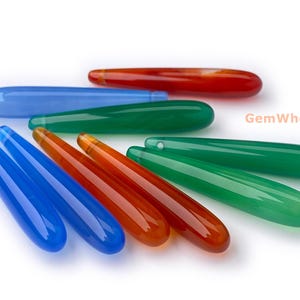 May include: A selection of polished gemstone pendants in shades of blue, green, and orange. The teardrop-shaped pendants have a smooth, glossy finish. The image includes the text "GemWholesale".
