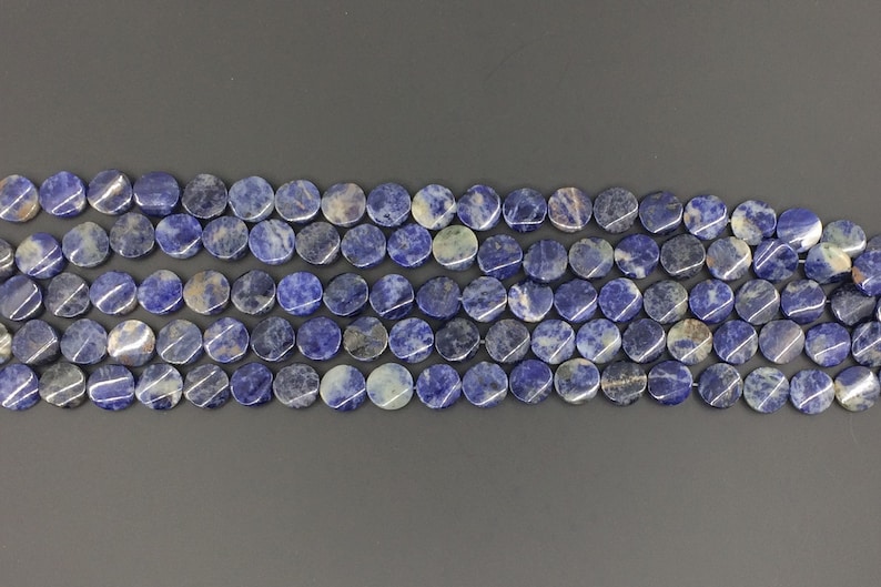 May include: A strand of round, blue and white gemstone beads. The beads are smooth and polished, with a natural, mottled appearance.