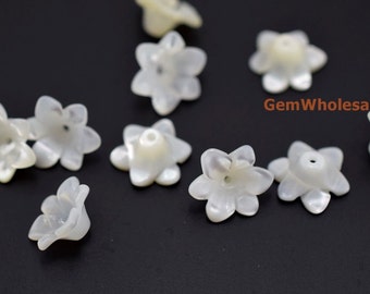Könnte beinhalten: Weiße Perlmutt-Blumenperlen. Die Perlen sind in Form von fünfblättrigen Blüten mit einem Loch in der Mitte. Die Perlen haben einen Durchmesser von etwa 2,5 cm.