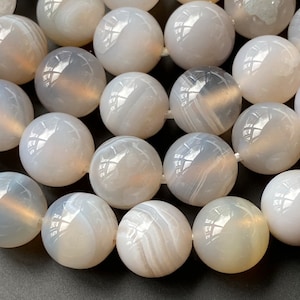 May include: A strand of white agate beads with a smooth, polished finish. The beads are round and have a subtle, translucent quality.