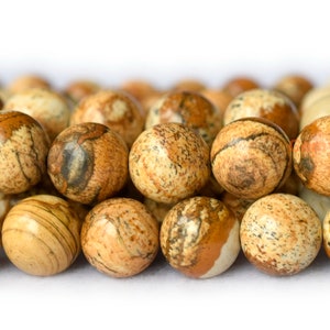 Pode incluir: Um fio de contas de jaspe marrom e branco. As contas são redondas e têm um acabamento natural e polido.