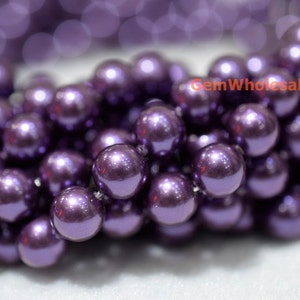May include: A close-up of a strand of purple pearl beads. The beads are round and have a smooth, shiny finish.