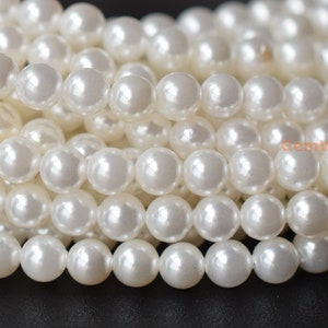 Puede incluir: Una hebra de cuentas de perlas blancas. Las cuentas son redondas y lisas, y tienen un acabado brillante.