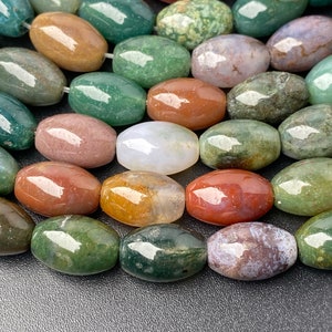 May include: A collection of oval-shaped agate beads in various shades of green, brown, red, and white. The beads have a smooth, polished finish and are arranged in a row.