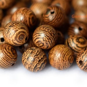 May include: Close-up of a pile of brown wooden beads with a striped pattern. The beads have a hole drilled through the center.