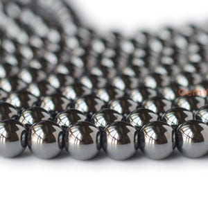 May include: A strand of shiny, black hematite beads. The beads are round and smooth, and they have a metallic sheen.