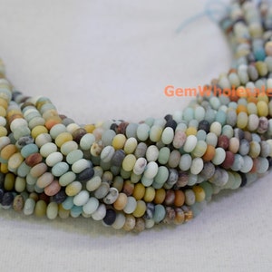 May include: Strands of Amazonite gemstone beads in a variety of colors, including shades of blue, green, yellow, and brown. The beads are small, round, and have a smooth texture. The beads are strung together, creating a necklace or bracelet.