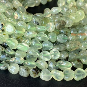 Könnte beinhalten: Eine Strähne aus hellgrünen Edelsteinperlen mit einer glatten, kieselsteinartigen Form. Die Perlen sind durchscheinend mit dezenten Einschlüssen.