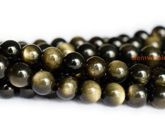 May include: A strand of round, black and gold beads with a shimmering, iridescent finish. The beads are smooth and polished, and they have a subtle sparkle.