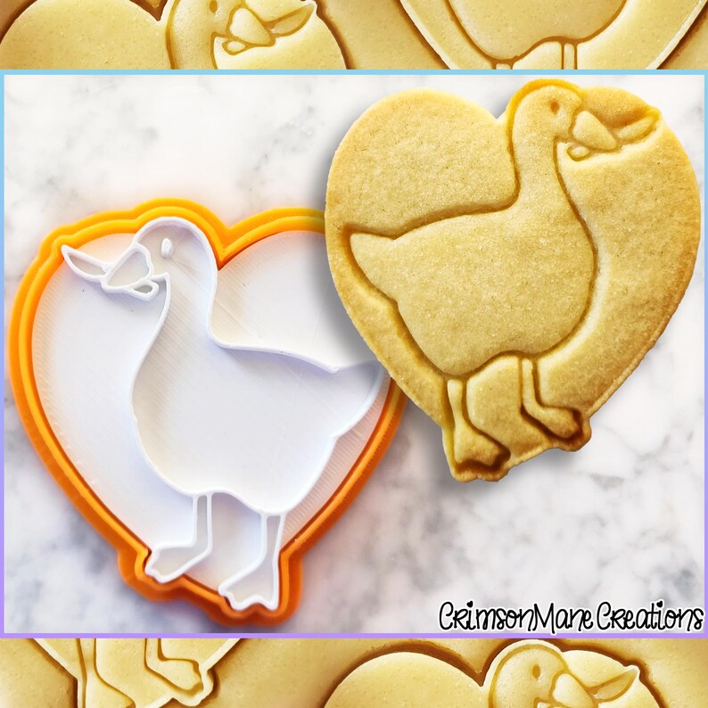May include: A heart-shaped cookie with a goose design next to a white and orange cookie cutter. The cookie is light brown and the goose is clearly defined. The cookie cutter is white with an orange border. The text "Crimson Mane Creations" is in the bottom right corner.