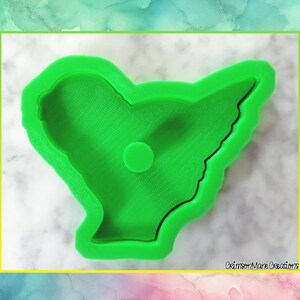 May include: Bright green cookie cutter in the shape of a stylized bird. The cutter has a smooth, rounded edge and a small circular detail in the center. The words "Crimson Mare Creations" are printed in the bottom right corner.