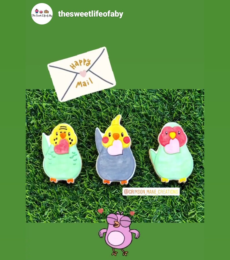 May include: Three decorated sugar cookies shaped like parakeets, each holding a heart. The cookies are on a green grass background. An envelope with the words "Happy Mail" is above the cookies. A pink cartoon bird with hearts around its head is at the bottom of the image. The text "@crimson_mane_creations" is below the cookies.