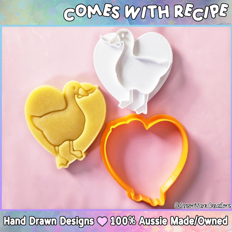 May include: A heart-shaped cookie cutter set with a duck design. The set includes a yellow cookie, a white cutter, and an orange outline cutter. The text "COMES WITH RECIPE" is at the top. The bottom text reads "Hand Drawn Designs 100% Aussie Made/Owned."