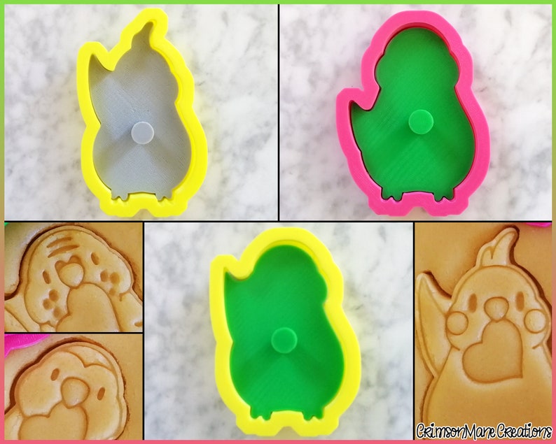 May include: Four cookie cutters in the shape of a bird. Two are yellow with a green bird inside, and two are pink with a gray bird inside. The cutters are shown next to cookies that have been cut with the cutters.